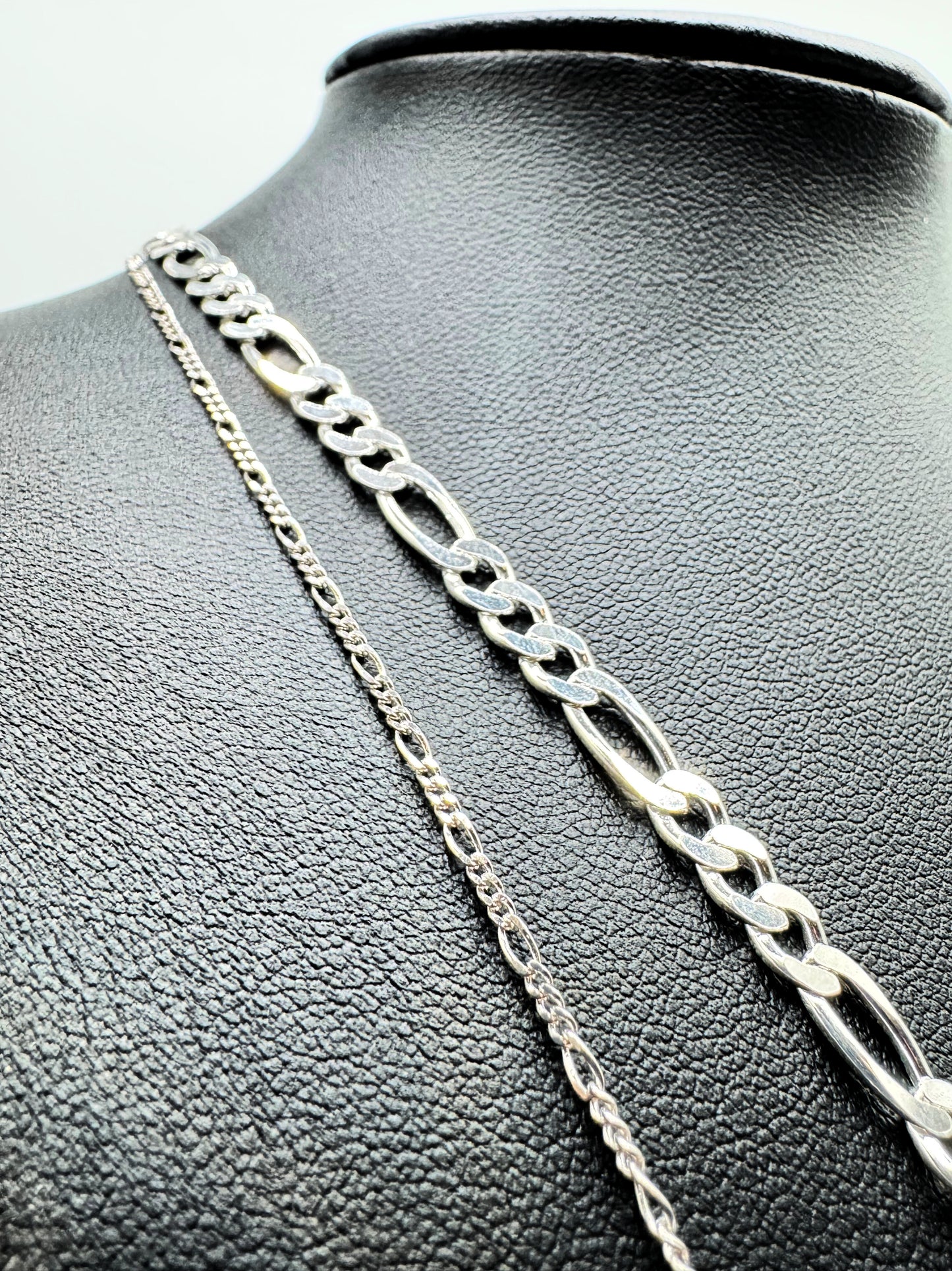 Feine Figaro-Kette aus 925er Sterling Silber mit hochwertigem Diamond-Cut, präsentiert auf einer edlen schwarzen Leder-Schmuckpuppe. Die glänzende, filigrane Gliederkette überzeugt mit ihrem zeitlosen Design und luxuriösem Finish. Perfekt als modisches Accessoire für Damen und Herren, ideal für den Alltag oder besondere Anlässe.