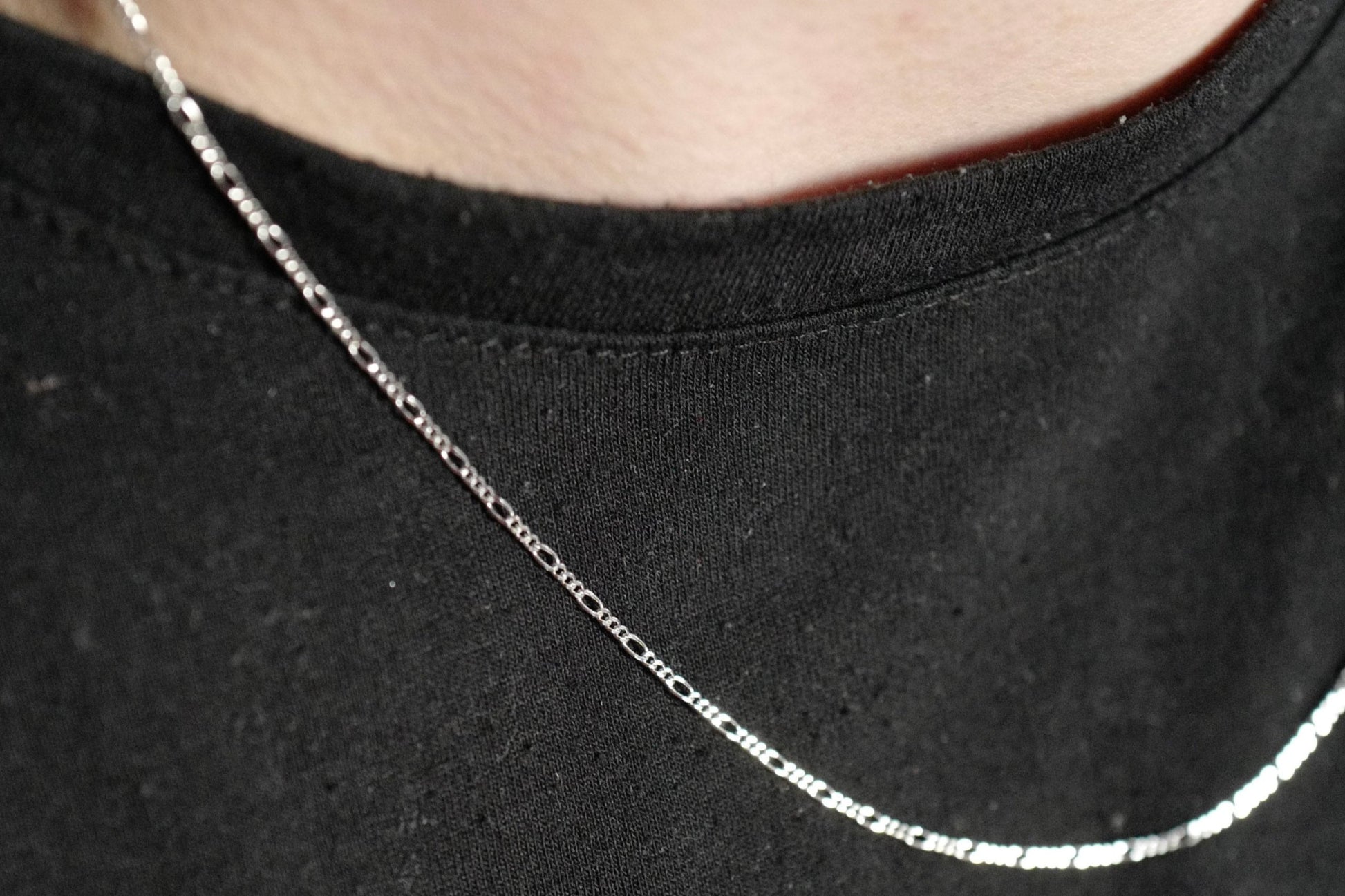 Elegante Figaro-Kette aus 925er Silber mit Diamond-Cut, getragen von einem Live-Model. Die filigranen, polierten Glieder reflektieren das Licht und verleihen der Kette einen edlen Glanz. Durch ihr zeitloses Design ist sie sowohl für Damen als auch Herren geeignet – perfekt für den Alltag oder besondere Anlässe. Ideal als modisches Accessoire oder stilvolles Geschenk.