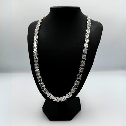 Massive 925er Sterling Silber Königskette, ein zeitloses Schmuckstück für Herren. Die Kette besticht durch ihre robuste Verarbeitung und das kunstvolle Design, typisch für eine hochwertige Königskette.  Das glänzende Sterlingsilber sorgt für einen edlen Look. Die Kette wird auf einer eleganten, schwarzen Schmuckpuppe vor einem neutralen, weißen Hintergrund präsentiert, um die Details optimal hervorzuheben. Diese Königskette ist ein Statement-Piece, das jedem Outfit einen Hauch von Luxus verleiht.